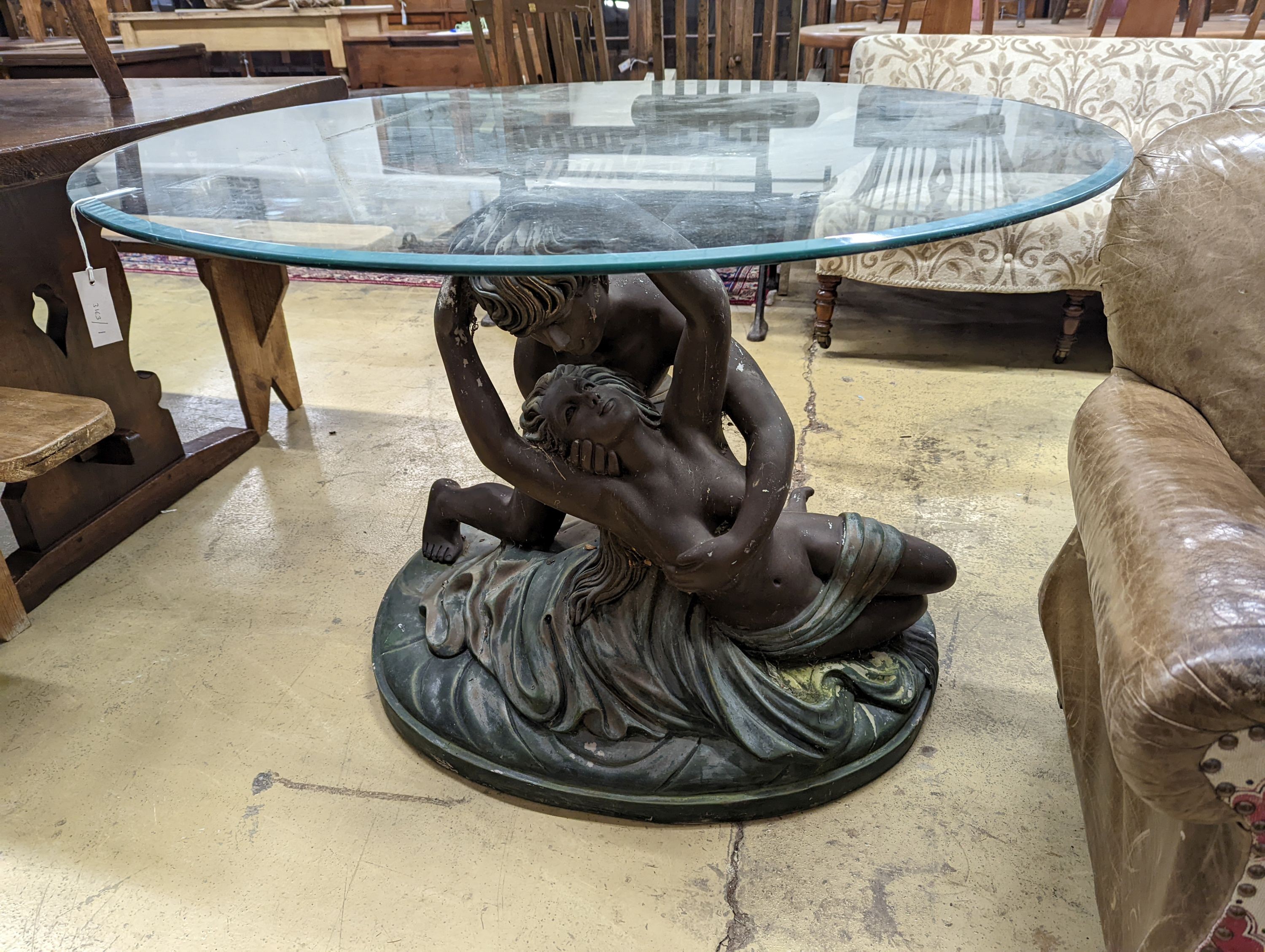 A bronzed composition glass top figures table. Diameter - 122cm, Height - 76cm.